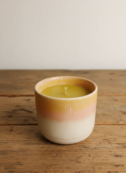 Bienenwachskerze im pinken Keramikbecher auf dem Tisch