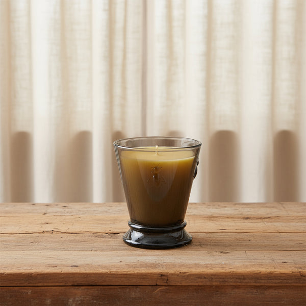 Bienenwachskerze im violetten Glas auf dem Tisch